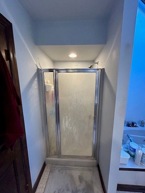 A bathroom with a walk in shower and a sink