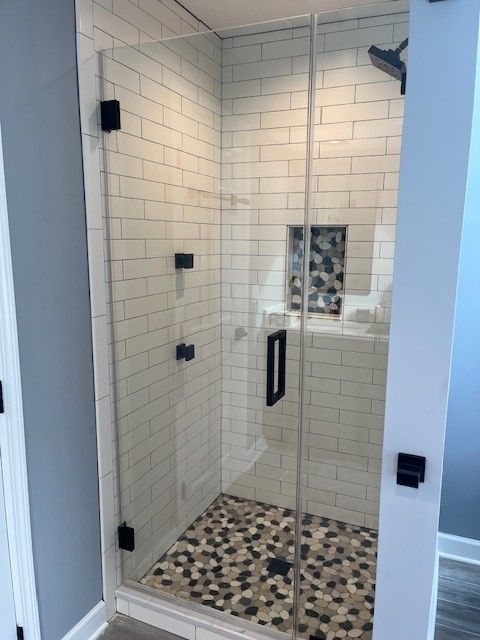 A bathroom with a walk in shower with a glass door