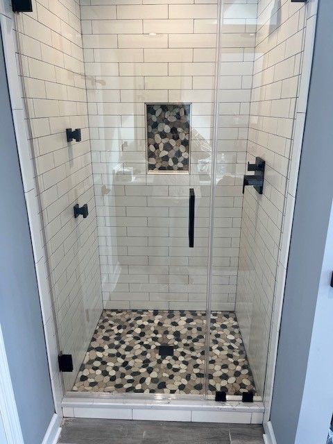 A shower with a tiled floor and a glass door