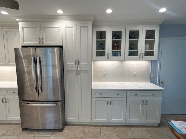 A kitchen with white cabinets and a stainless steel refrigerator