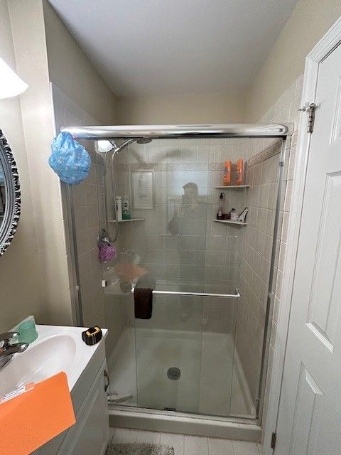 A bathroom with a walk in shower and a sink