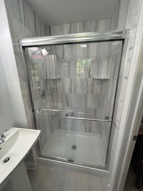 A bathroom with a sliding glass shower door and a sink