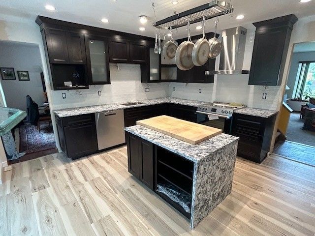 A kitchen with a large island in the middle and pots and pans hanging from the ceiling
