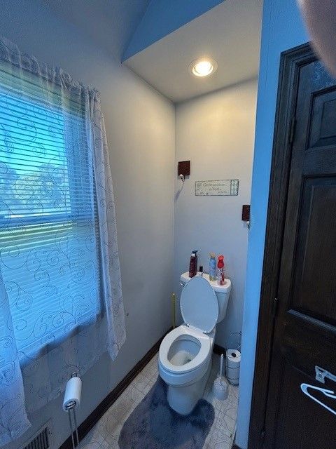 A bathroom with a toilet and a window with blinds