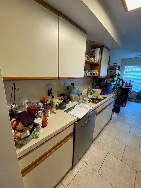 A kitchen with white cabinets and a stainless steel dishwasher