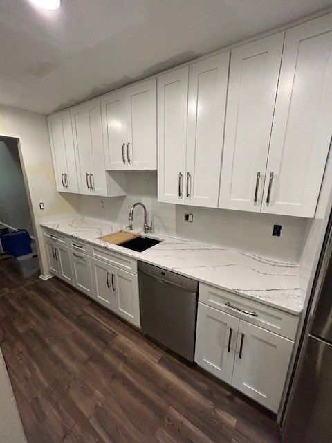 A kitchen with white cabinets, a sink, and a stainless steel dishwasher