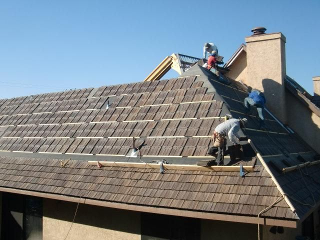 Roofers installing new shingles on a residential roof.
