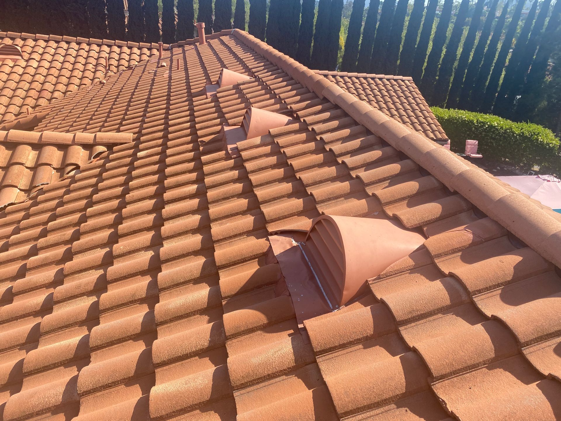 Brown clay tile roof with curved tiles and air vents, angled upward.
