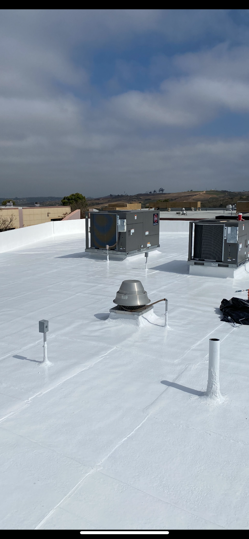 White commercial roof with HVAC units and blue sky.