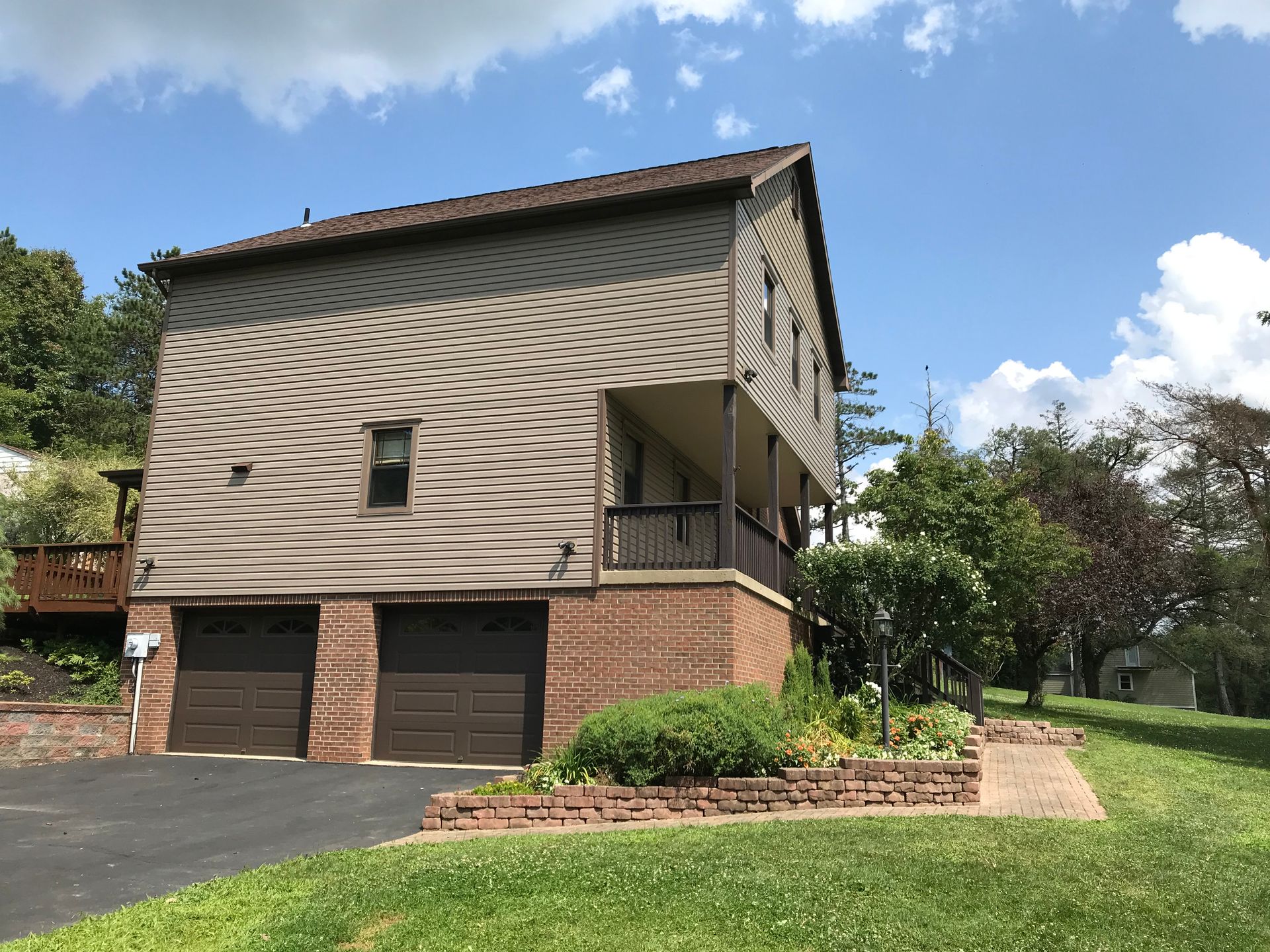 a house with two garage doors and a porch on a sunny day