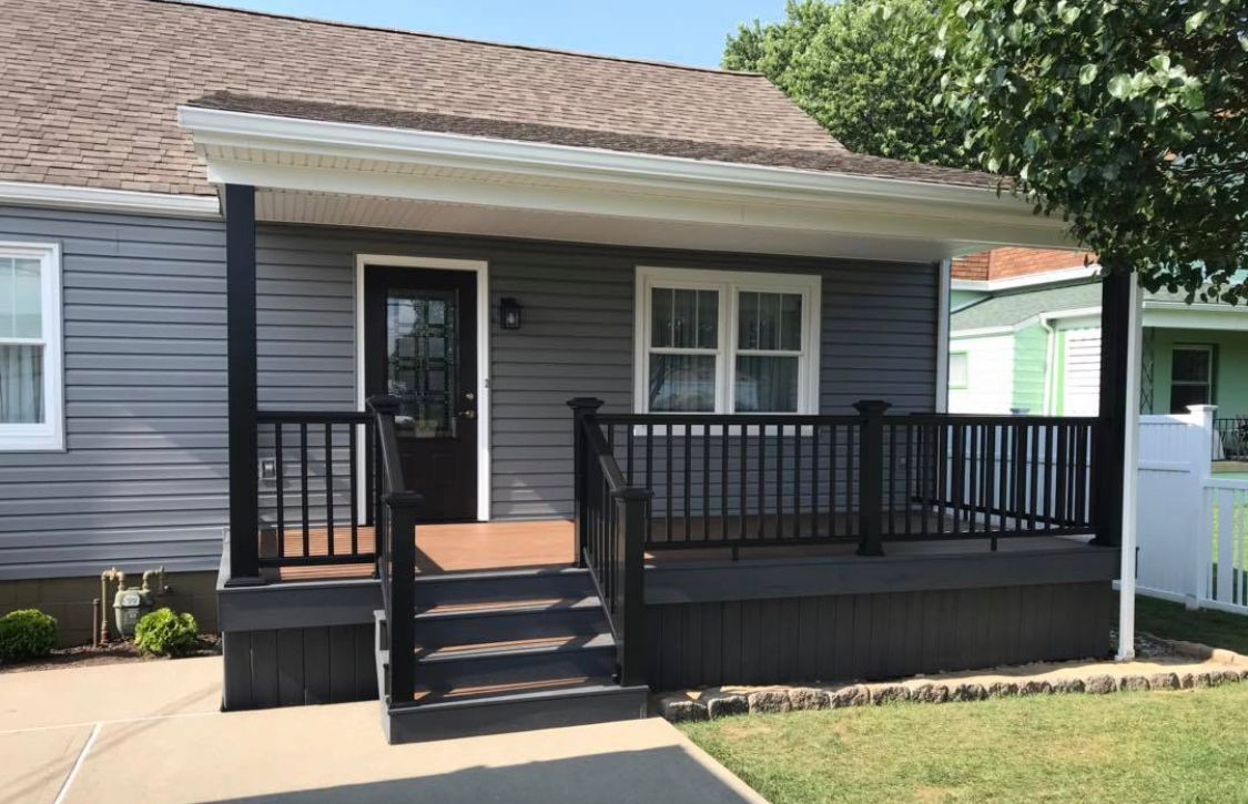 a gray house with a black porch and stairs leading up to it
