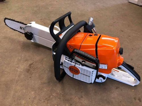 Orange and white Stihl chainsaw on a brown surface.