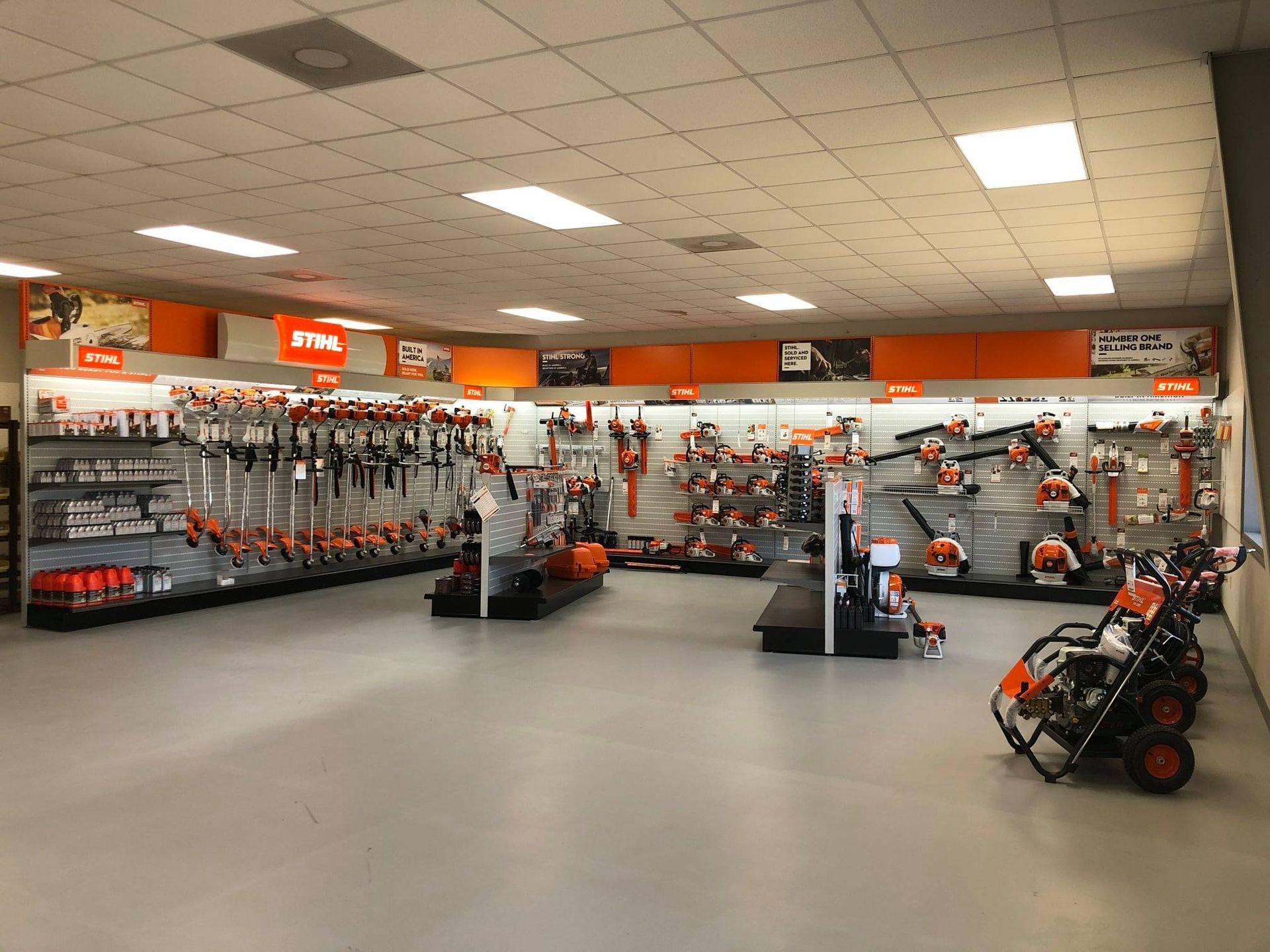 Interior of a Stihl power tool store, showcasing various orange and gray equipment on shelves and display.