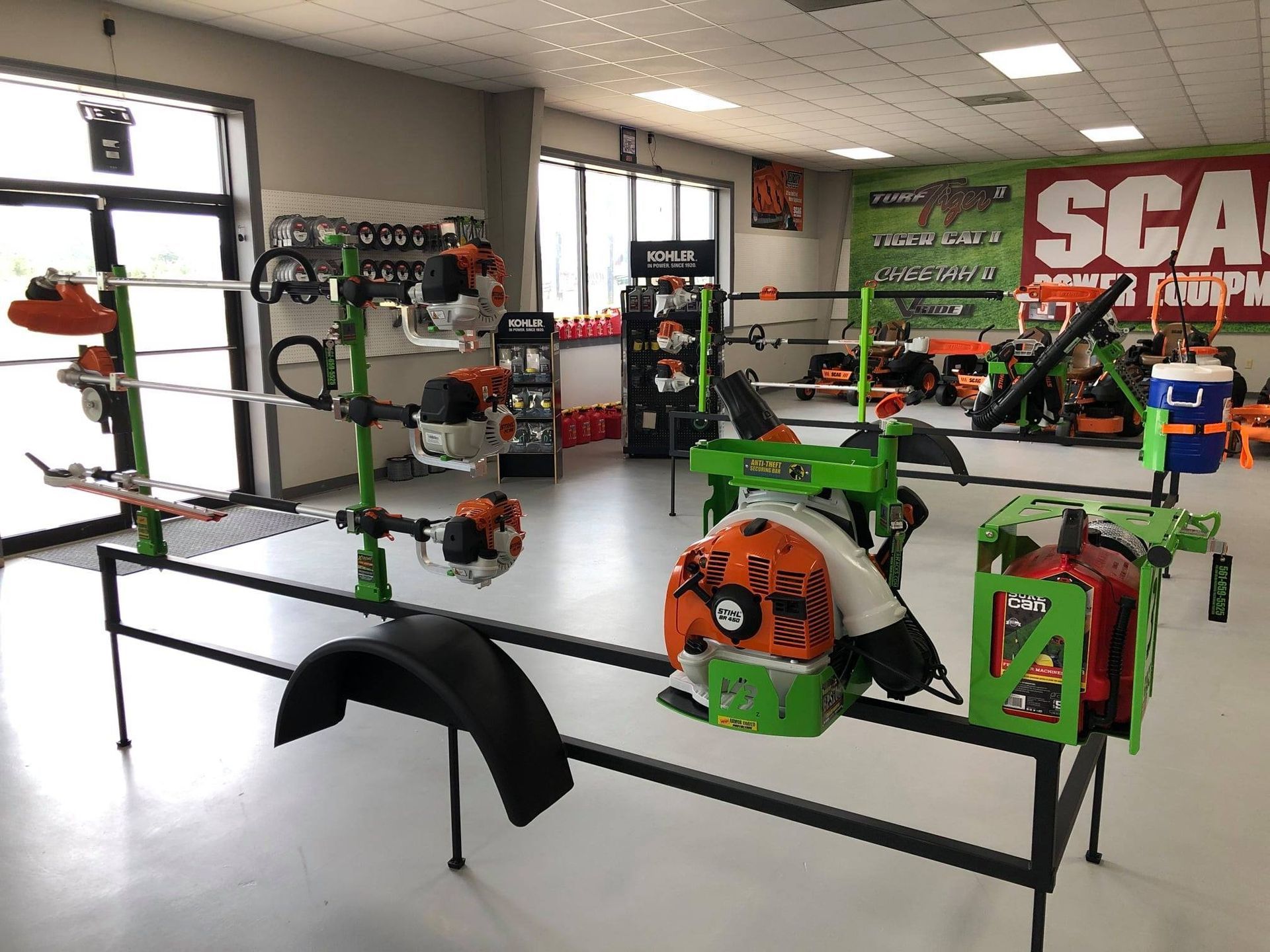 Inside a lawn equipment store; various orange and green tools displayed on racks.