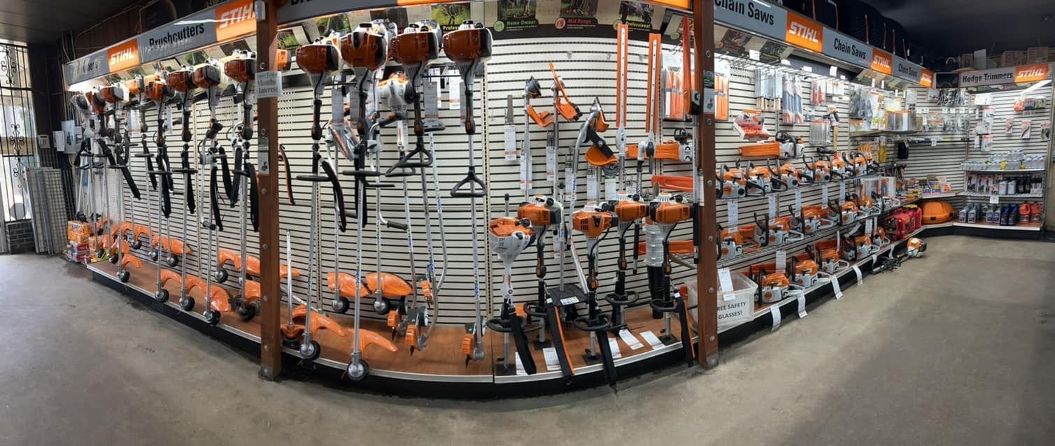 A retail display of orange and black lawn tools, including trimmers and blowers, in a store.
