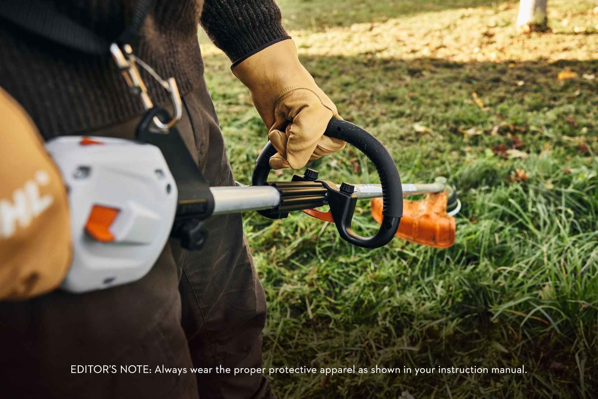 Person in gloves operating a string trimmer on a grassy lawn.