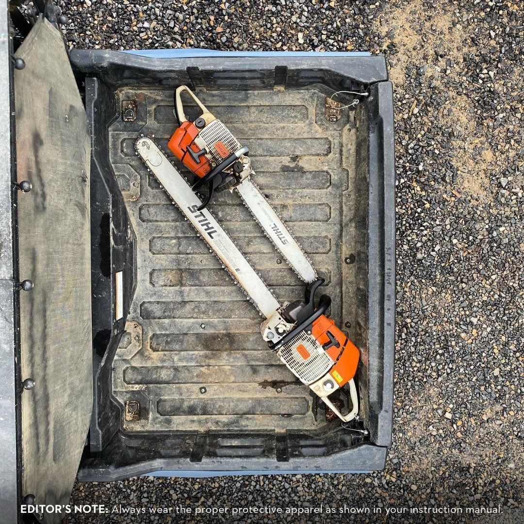 Two Stihl chainsaws inside a dark, open truck bed.
