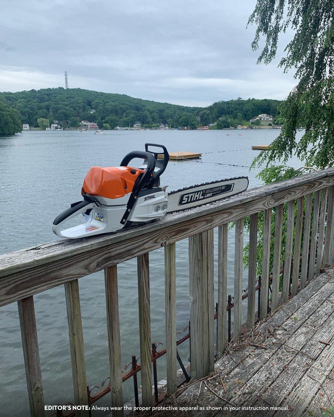 Chainsaw on a wooden deck overlooking a lake with a cloudy sky.