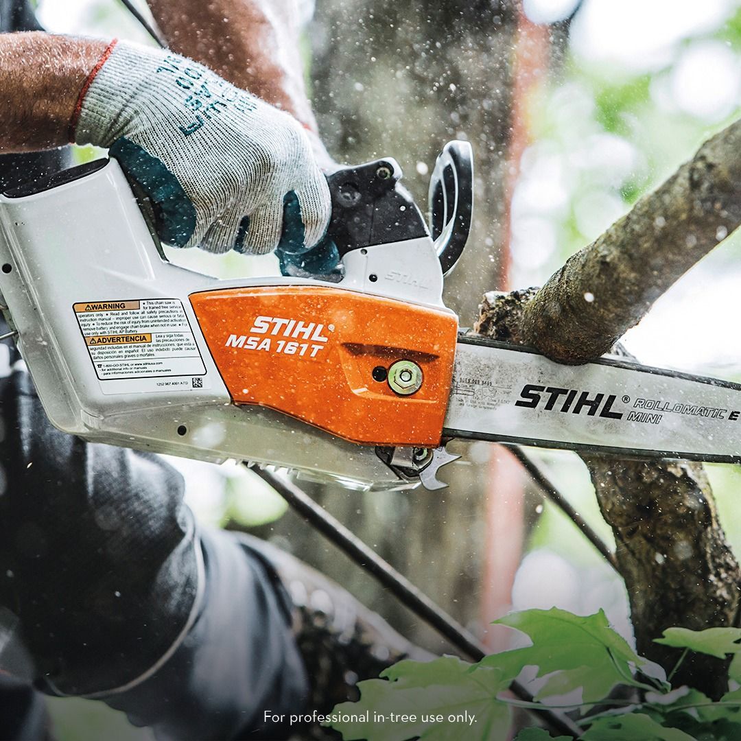 Person using a Stihl MSA 161 T chainsaw to cut a tree branch.