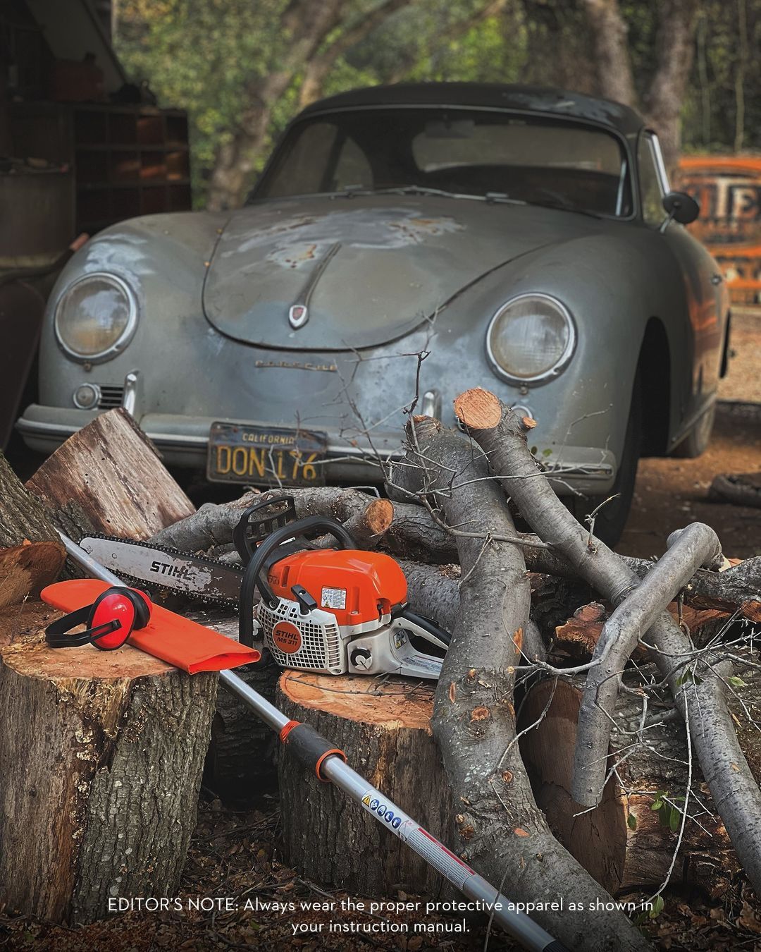 Old, weathered silver car behind a chainsaw and firewood. Outdoor setting.