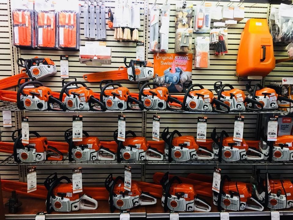 Chainsaws displayed on shelves in a retail store; orange and silver color scheme.