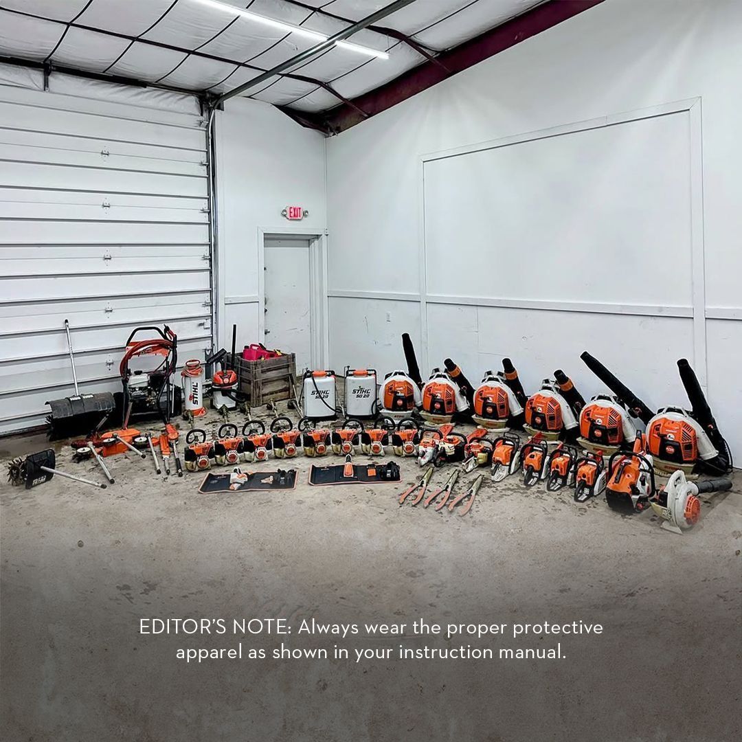 A collection of Stihl leaf blowers and tools arranged in a garage with a safety warning.