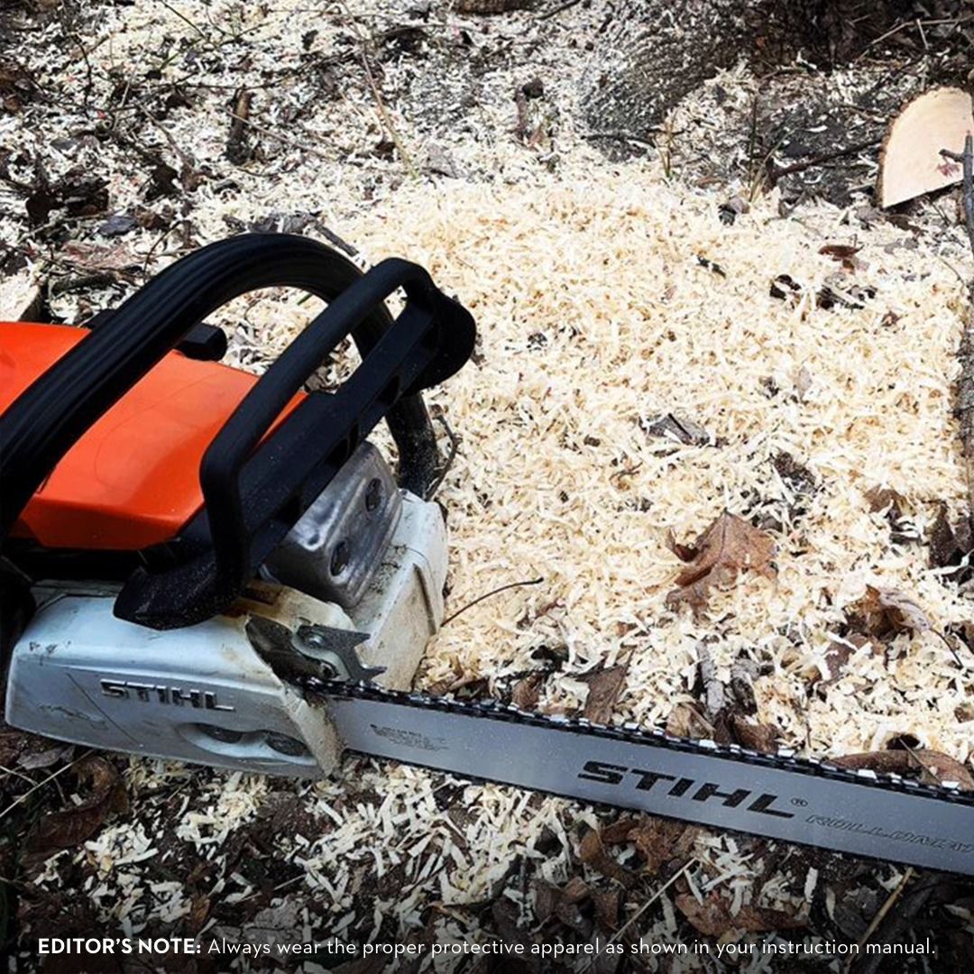 Orange and silver STIHL chainsaw with wood shavings on the ground.