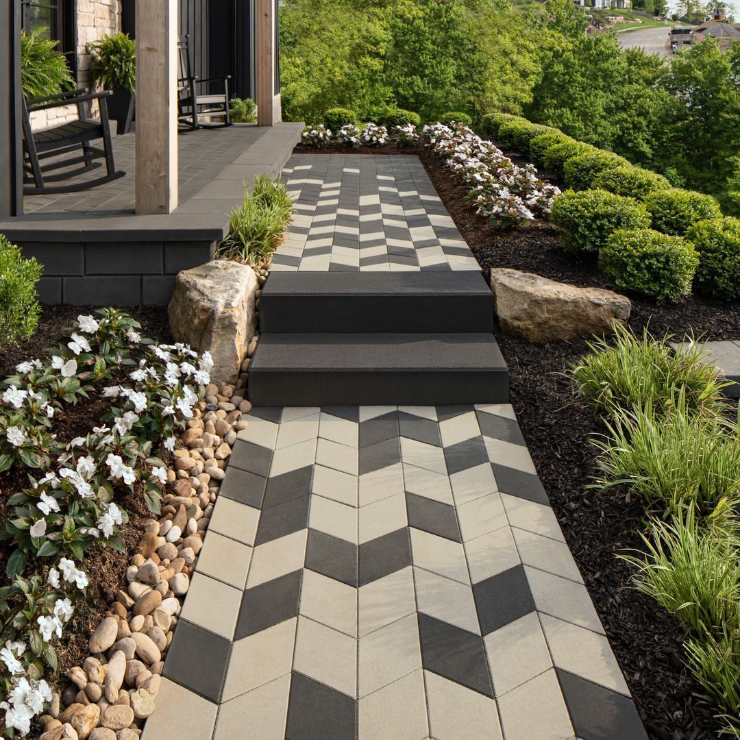 Modern stone walkway with geometric pavers, steps, and landscaped garden borders