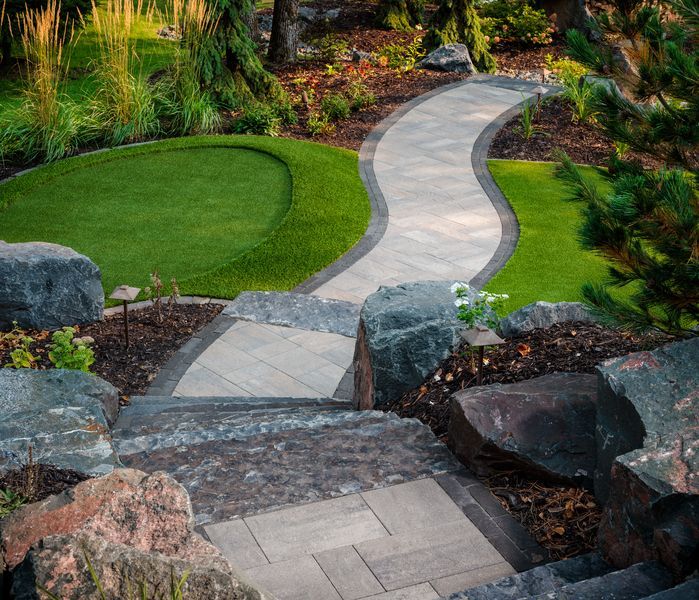 Curving stone garden path winding through landscaped greenery and rocks