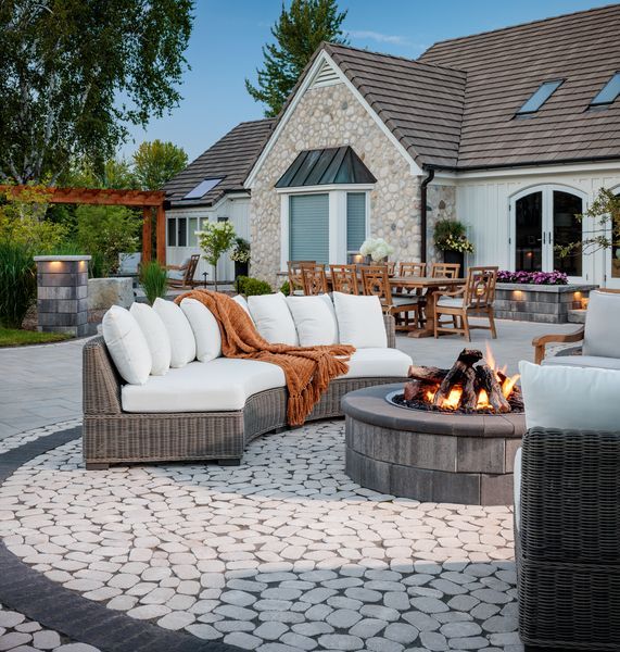 Patio with stone pavers, outdoor tables and chairs, and a red umbrella in a garden setting