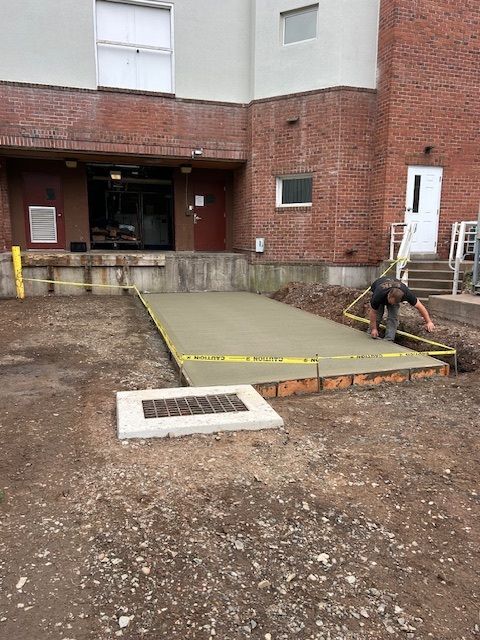 Newly poured concrete, outside the back of a red brick building.