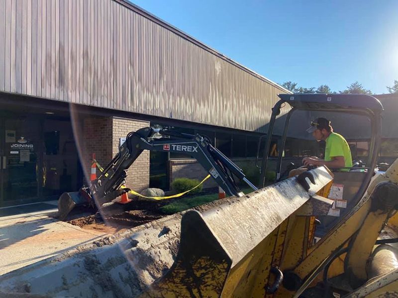 A terex excavator is digging a hole in the ground in front of a building