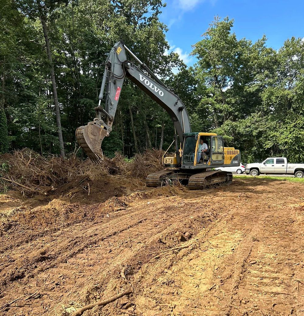 A volvo excavator is digging a hole in a dirt field
