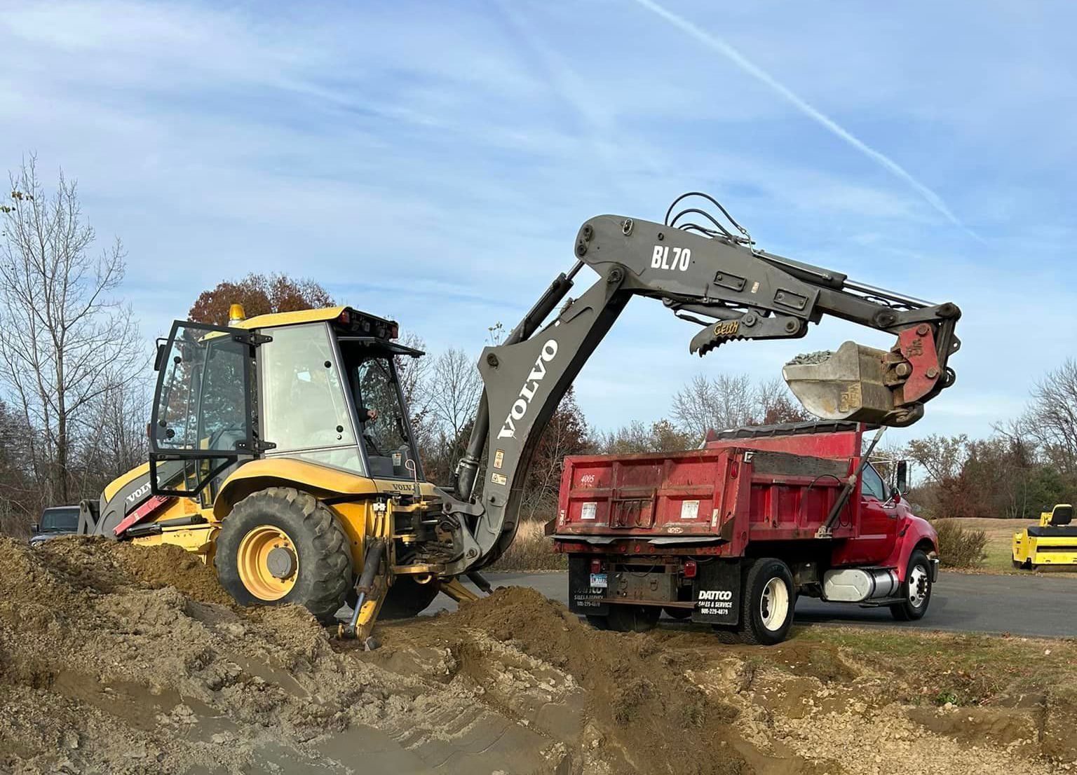 A volvo excavator is loading dirt into a dump truck