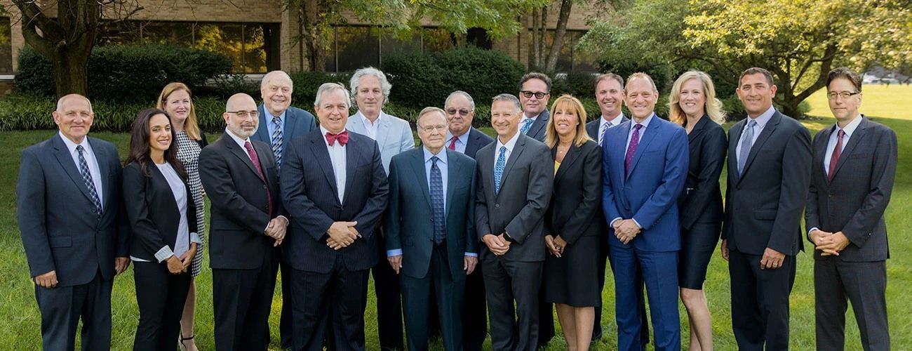 Group of people in suits posing outside.
