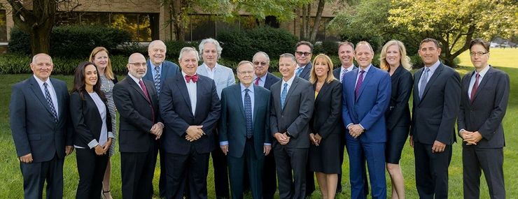 Group of people in suits posing outside.