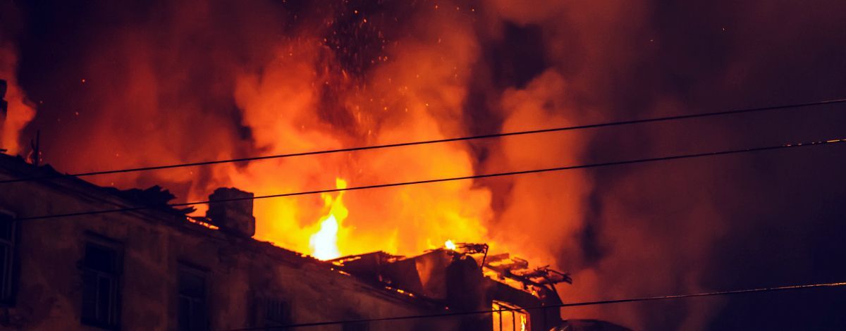 Building engulfed in flames, bright orange fire against a dark sky.