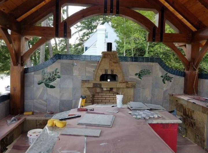 A wooden gazebo with a pizza oven in the background