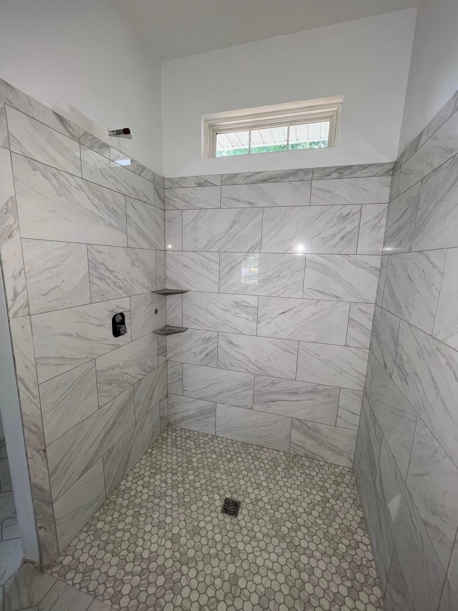 A bathroom with a walk in shower and a window.