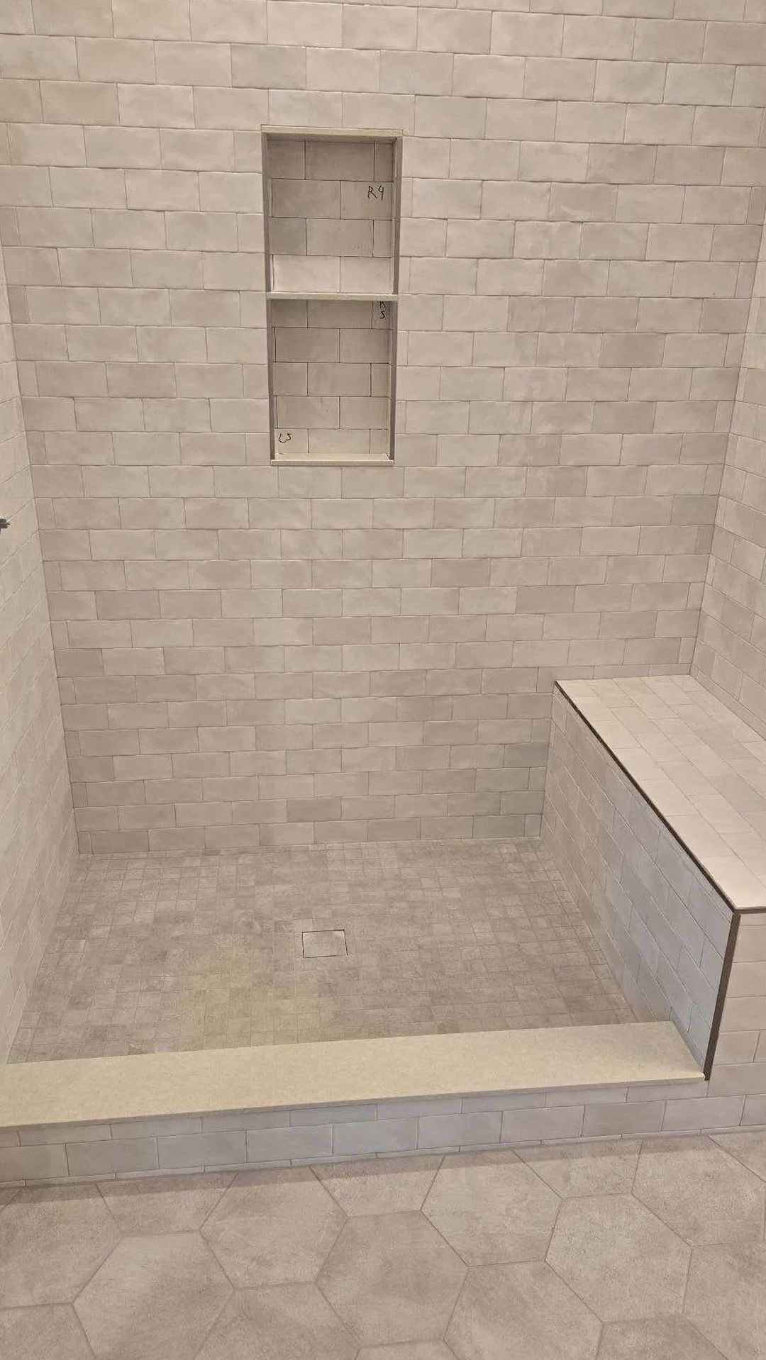 A bathroom with a walk in shower and a bench.