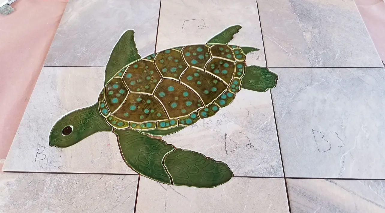 A green sea turtle is painted on a tile floor.