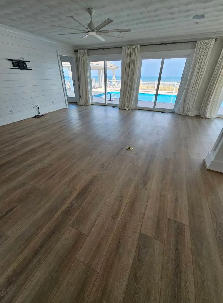 An empty living room with hardwood floors and a ceiling fan.