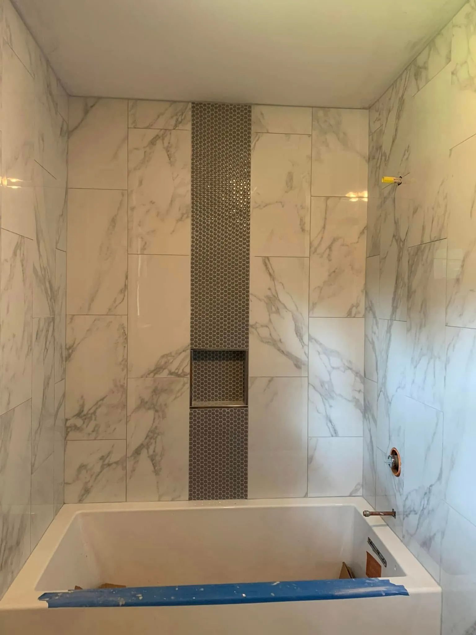 A bathroom with marble walls and a bathtub.