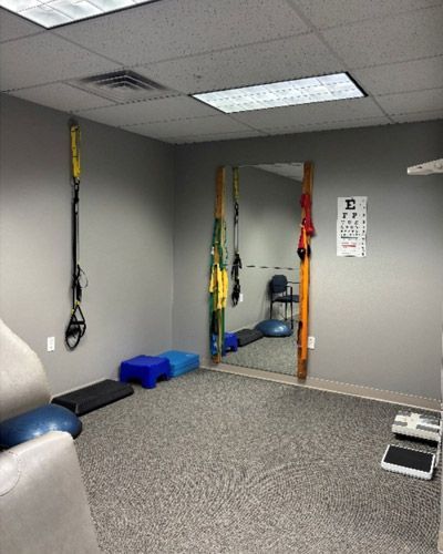 Physical therapy room with suspension straps, blue foam blocks, and carpeted floor