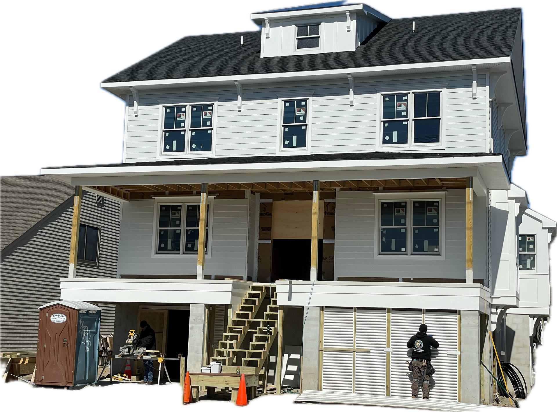 A large white house with a black roof is under construction.