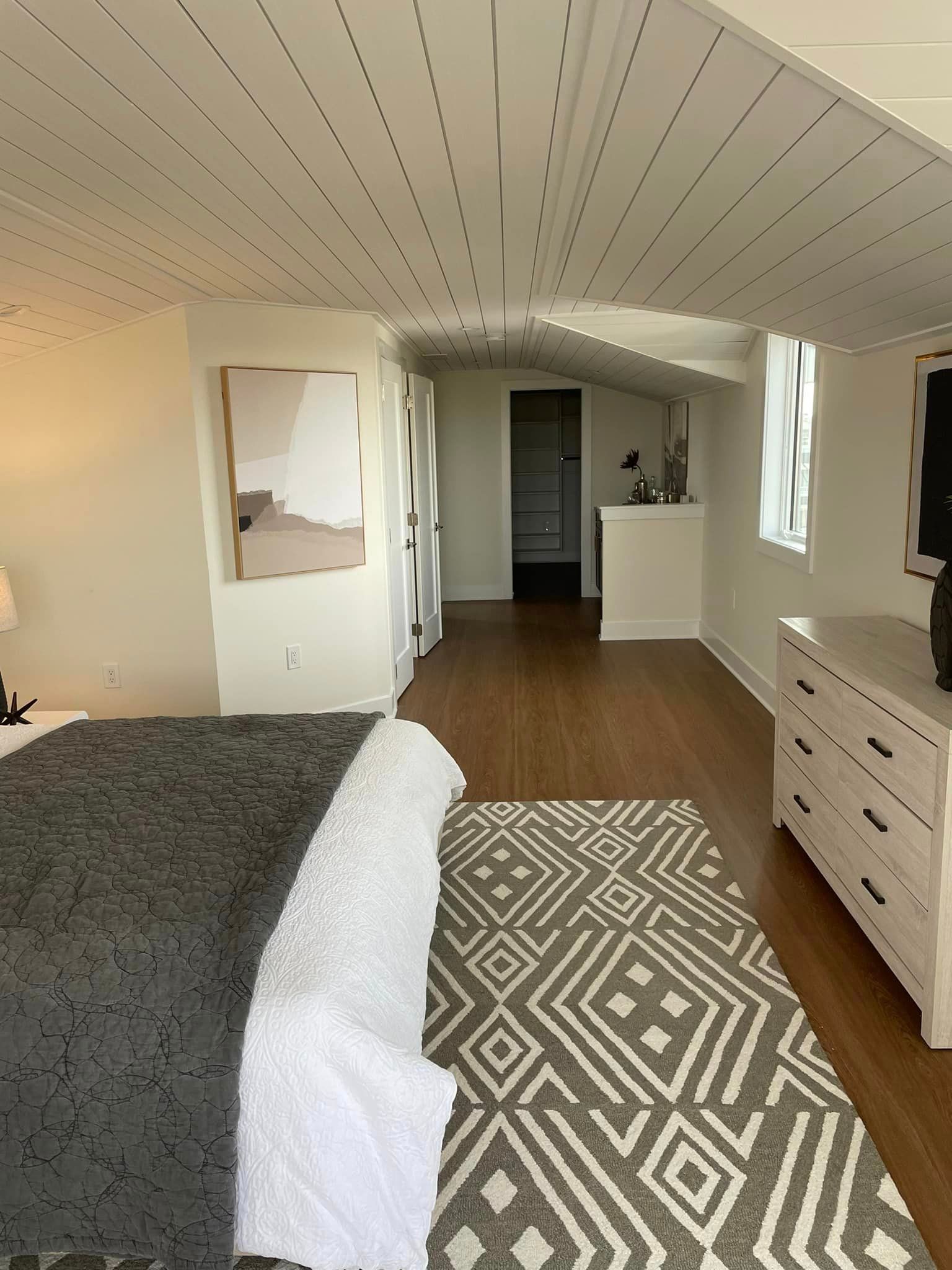 A bedroom with a bed, dresser, and rug.