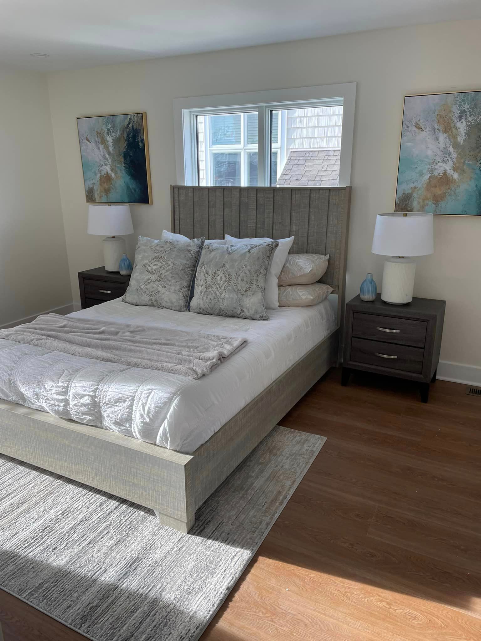 A bedroom with a bed, nightstands, lamps and a window.