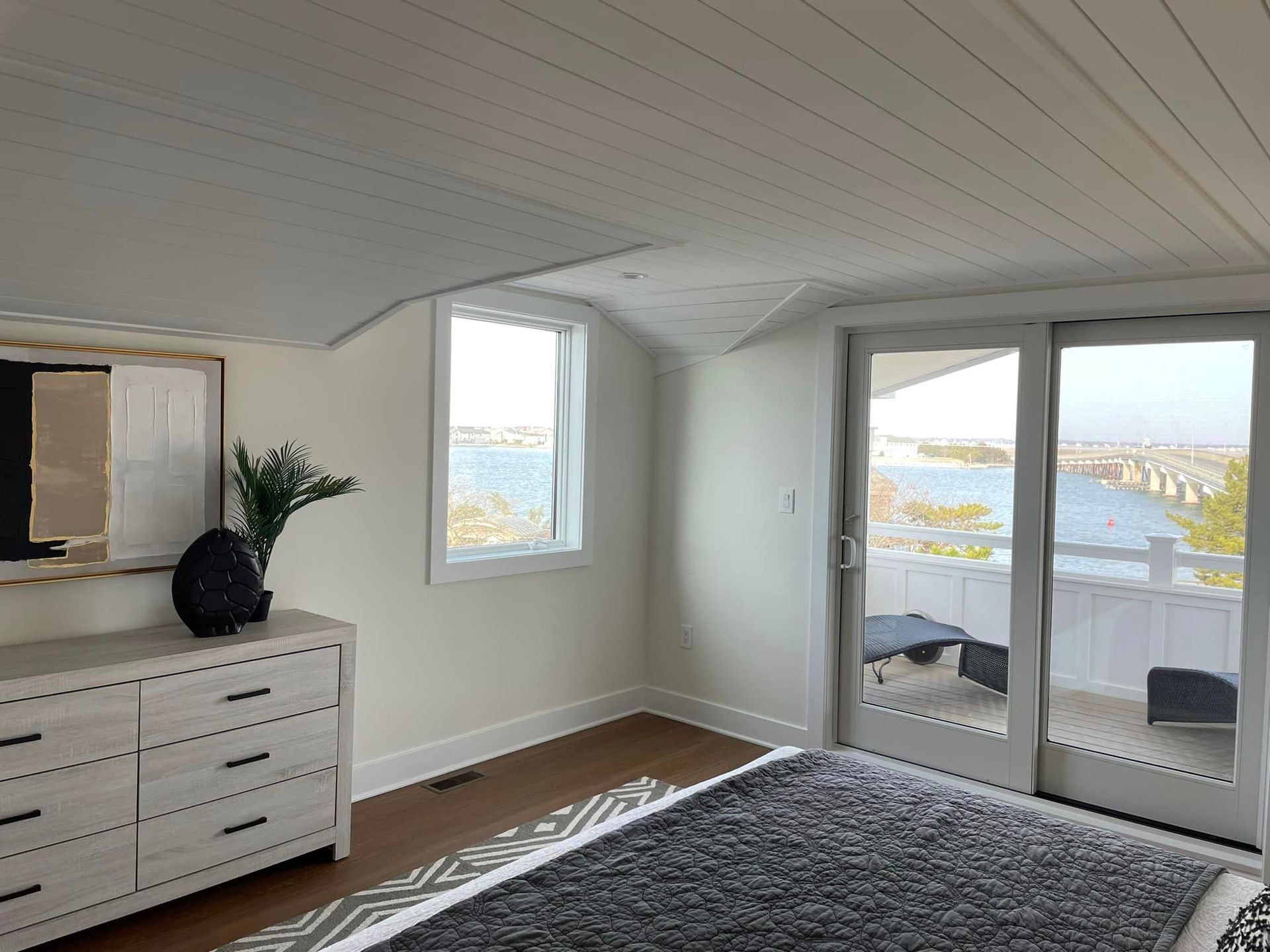 A bedroom with a dresser, rug, television and sliding glass doors.