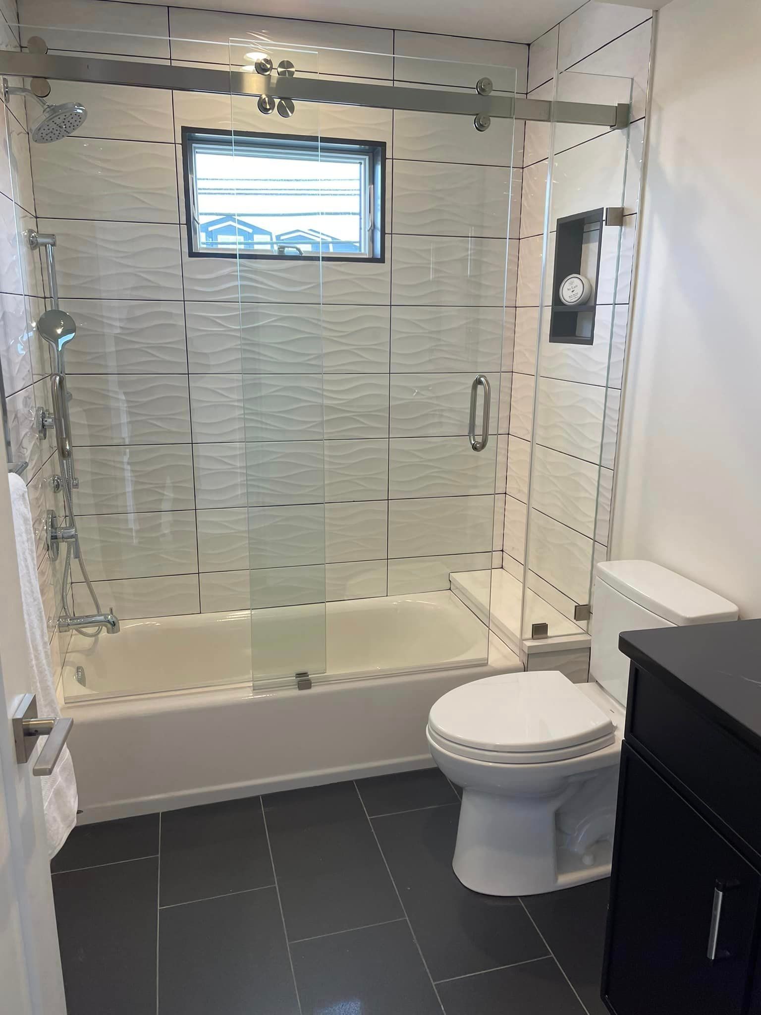 A bathroom with a toilet , tub, shower and window.