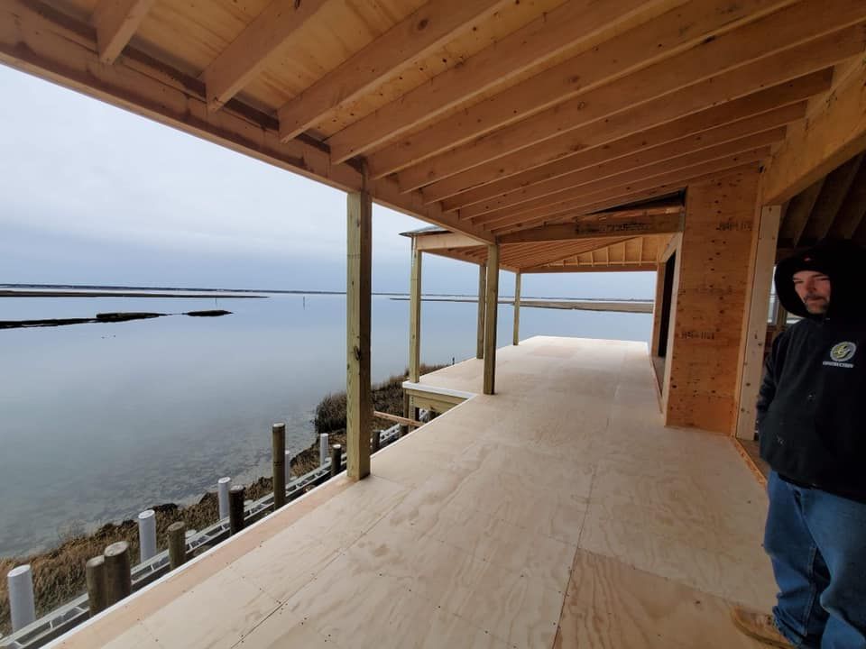 A man is standing on a deck overlooking a body of water.